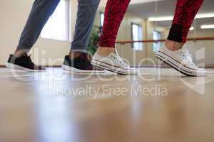 Low section of woman with friend rehearsing dance on floor