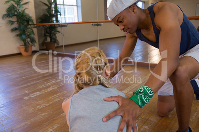 Man assisting female dancer in stretching on floor