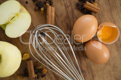 Close up of wire whisk by eggs with spices and granny smith apple