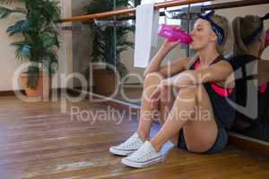 Full length of tired female dancer drinking water at studio