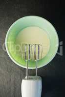Electric mixer by bowl with batter