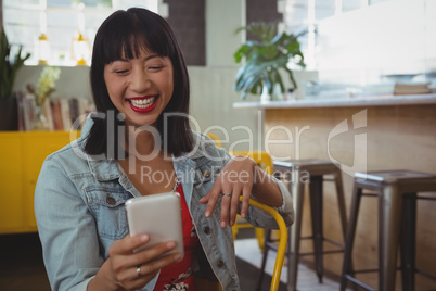 Happy woman using phone at cafe