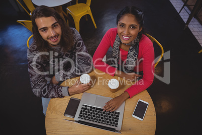 Portrait of friends with laptop in cafe