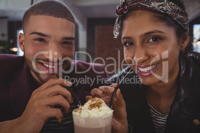 Portrait of friends enjoying milkshake in cafe