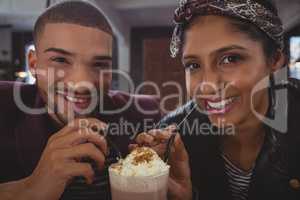 Portrait of friends enjoying milkshake in cafe
