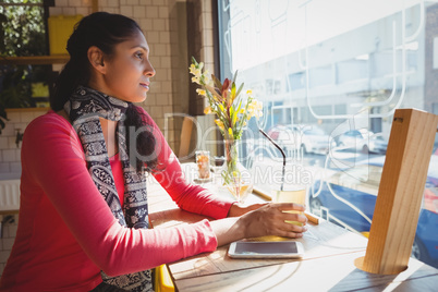 Thoughtful woman with drink at window sill in cafe