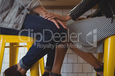 Low section of young couple on stool in cafe