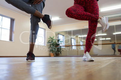 Low section of friends rehearsing dance on hardwood floor