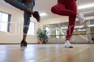 Low section of friends rehearsing dance on hardwood floor