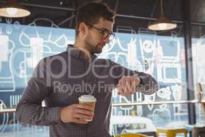 Businessman checking time while having coffee