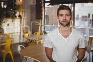 Portrait of confident waiter standing in cafe