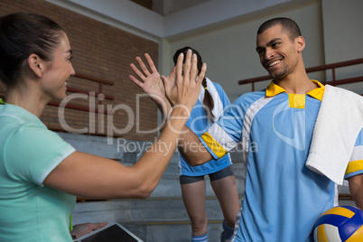 Coach giving high-five to male volleyball player