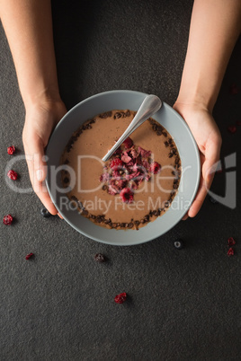 Hands holding a bowl of fruit cereal