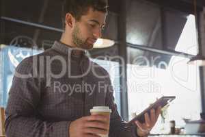 Businessman using tablet while having coffee