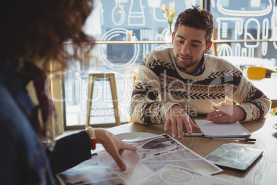 Man with woman discussing over chart in cafe