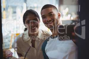 Man with woman taking selfie seen through glass in cafe