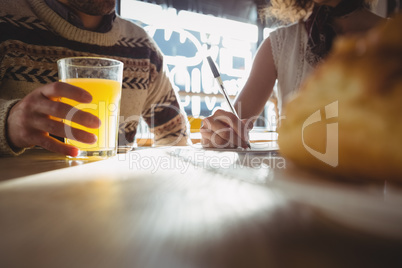 Midsection of man with woman having juice in cafe