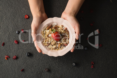 Hands holding a bowl of fruit cereal