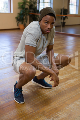 Full length portrait of dancer crouching in studio