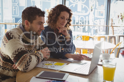 Business people using laptop at table in cafe