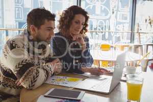 Business people using laptop at table in cafe