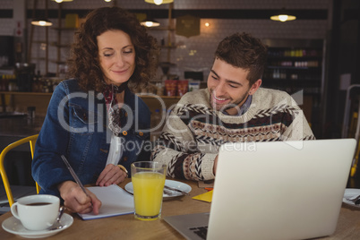 Businesswoman with man writing on paper in cafe