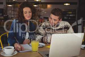 Businesswoman with man writing on paper in cafe