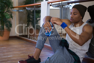 Tired male dancer holding water bottle at studio