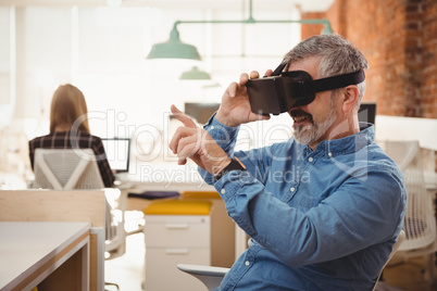 Male executive using virtual reality headset at desk
