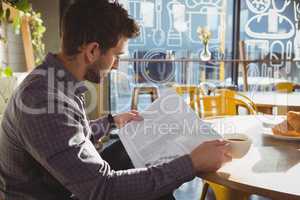 Businessman having coffee while reading newspaper in cafe