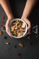 Hands holding a bowl of fruit cereal