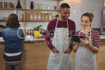Owner with man using tablet in cafe
