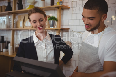 Waiter with owner looking into cash register in cafe
