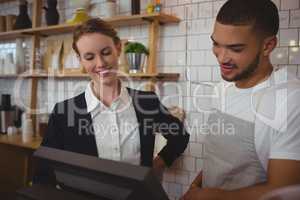 Waiter with owner looking into cash register in cafe