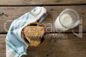 Granola bar and milk with napkin on wooden table