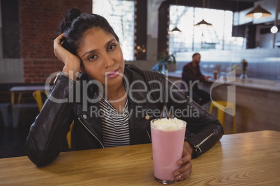 Portrait of woman holding milkshake glass with friend in background