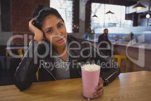 Portrait of woman holding milkshake glass with friend in background
