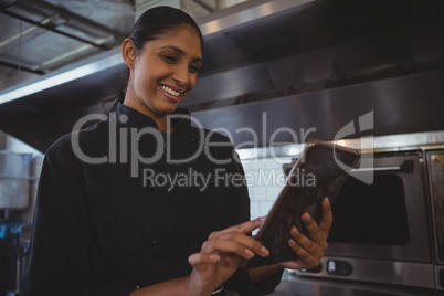 Happy waitress using tablet in cafe