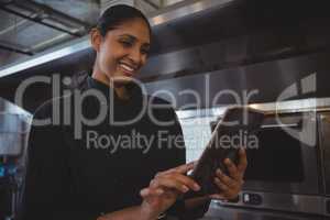 Happy waitress using tablet in cafe