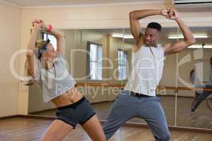 Friends rehearsing dance against mirror at studio