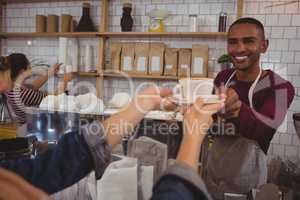 Cropped hands of customer receiving coffee from male owner