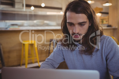 Young man using laptop in cafe