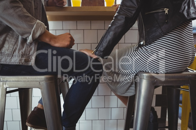 Low section of couple on stool in cafe