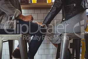 Low section of couple on stool in cafe