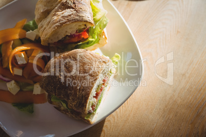 Sandwich and salad served in plate on table