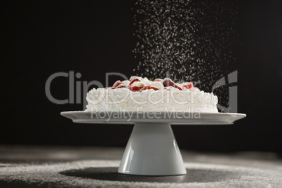 Powdered sugar falling over white cake on stand