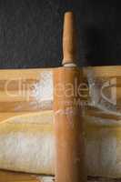 Close up of rolling pin on dough over cutting board