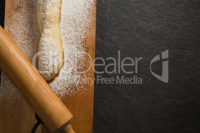 Raw bread and rolling pin with flour on cutting board