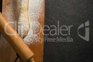 Raw bread and rolling pin with flour on cutting board