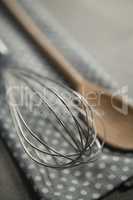 Close up of wire whisk with wooden spoon on napkin